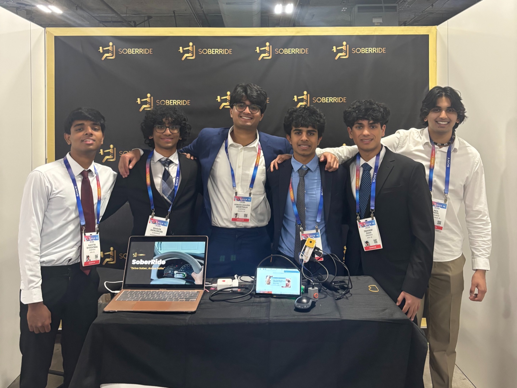 SoberRide booth at CES, team behind the demo table with CES badges