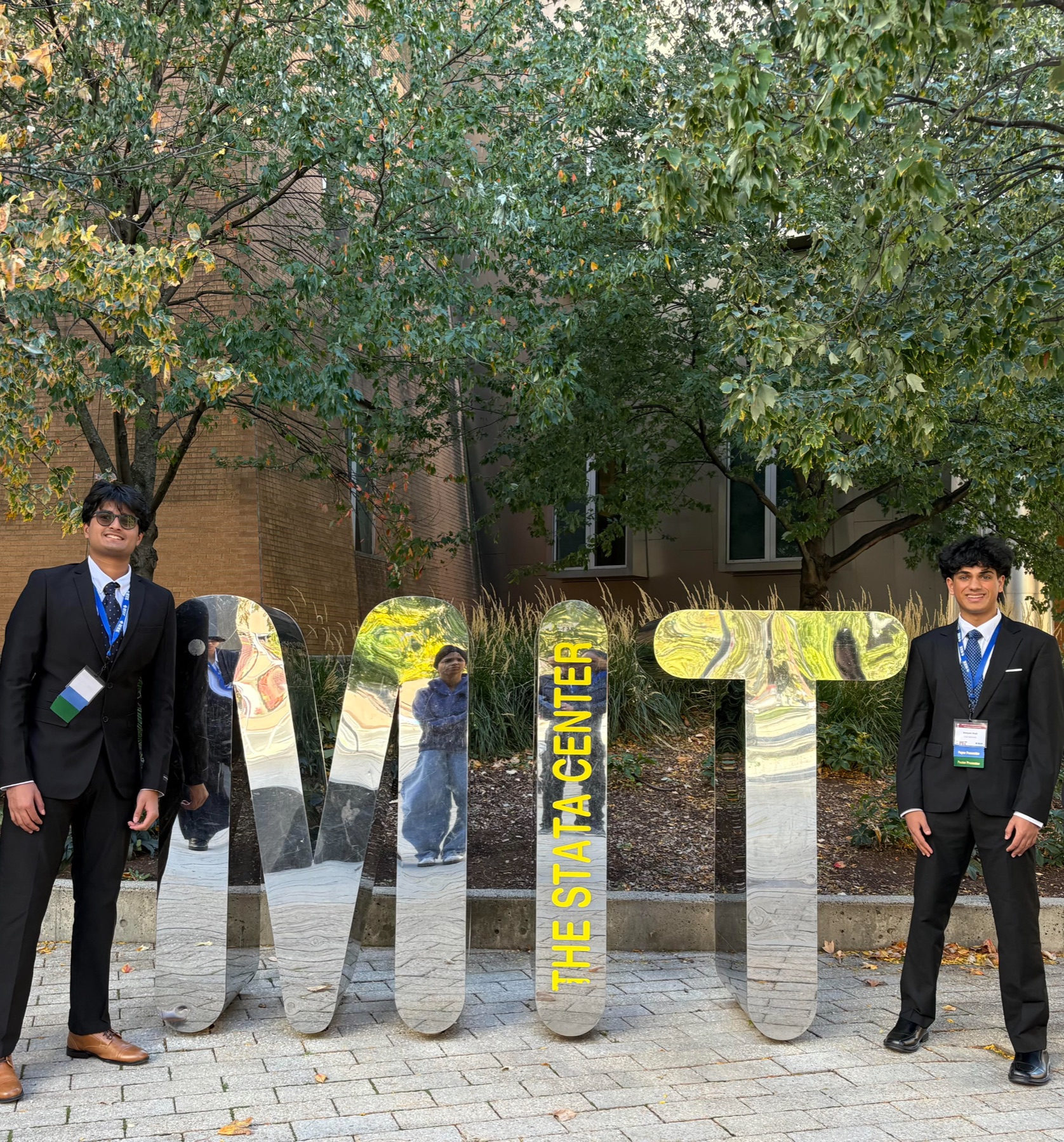 Two SoberRide founders in suits beside the MIT letters at the Stata Center